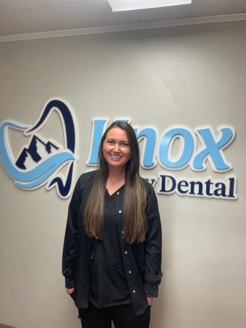 a woman stands in front of a nox dental sign