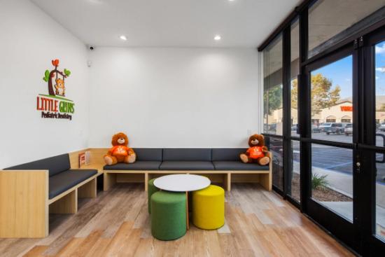 a waiting room with a couch , table , ottomans and teddy bears .