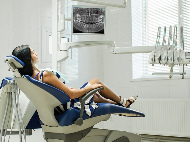 a woman sits in a dental chair with her legs crossed