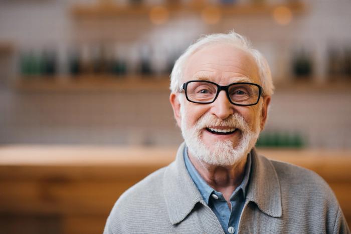 an elderly man with glasses and a beard is smiling for the camera .