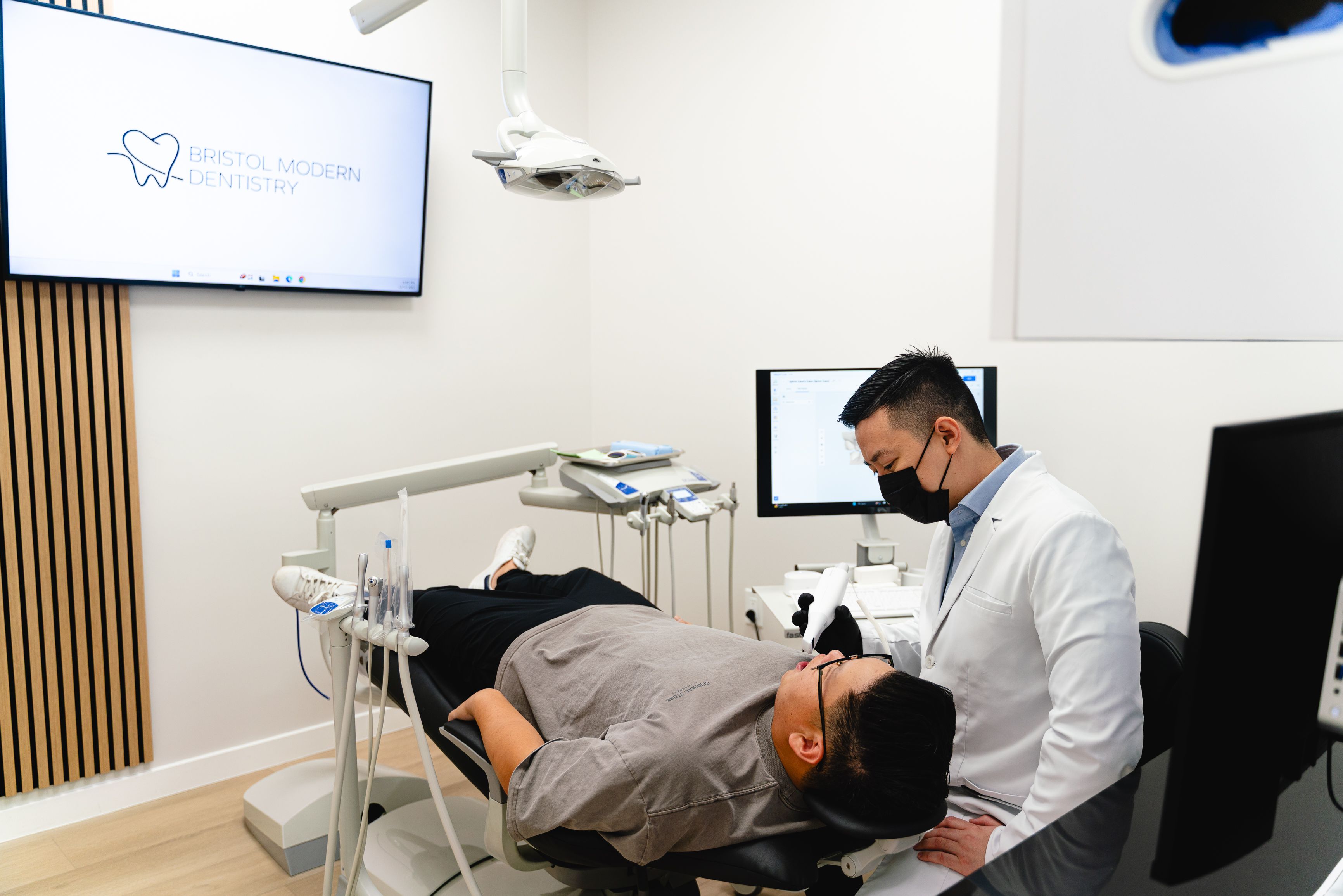 A dentist in a mask attends to a patient in a dental chair at Bristol Modern Dentistry.