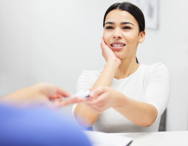 a woman is sitting at a table giving a business card to another woman .