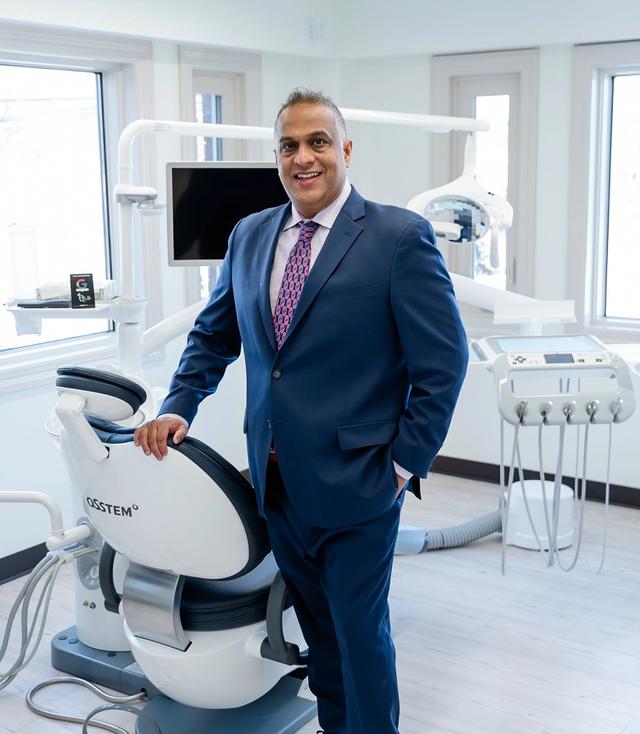 a man in a suit stands in front of a dental chair that says osstem