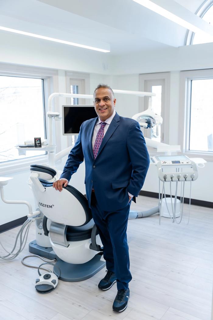 a man in a suit stands in front of a dental chair that says osstem