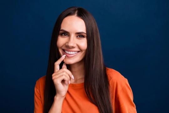 a woman with long hair is smiling with her hand on her chin .
