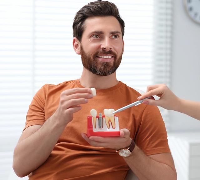 a man is holding a model of his teeth while talking to a dentist .