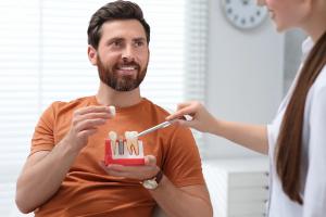 a man is holding a model of his teeth while talking to a dentist .
