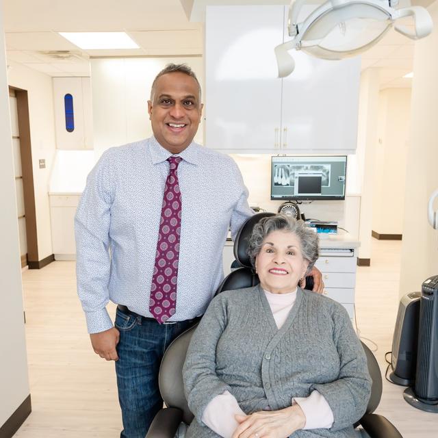 a man is standing next to a woman in a dental chair .