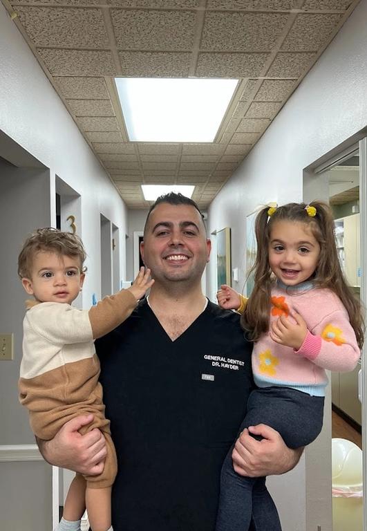 a man in a general dentist uniform holds two children