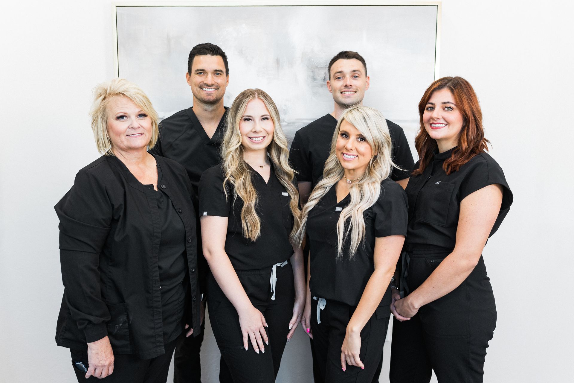 a group of people wearing black scrubs are posing for a picture .