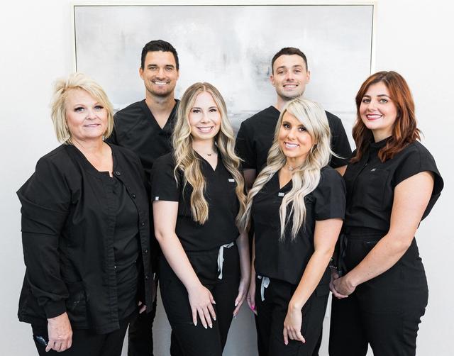 a group of people wearing black scrubs are posing for a picture .