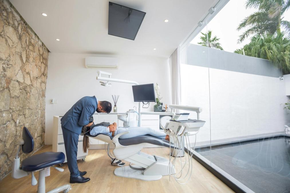 a dentist is examining a patient 's teeth in a dental office .