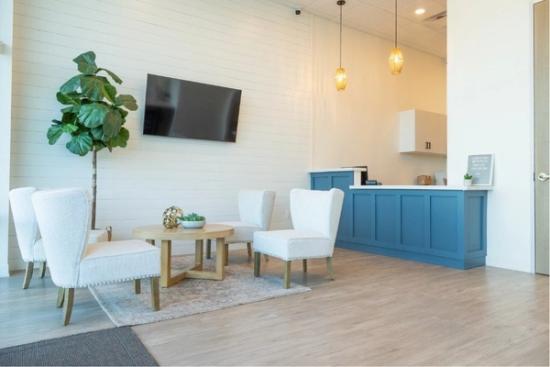 a waiting room with chairs , tables and a flat screen tv .