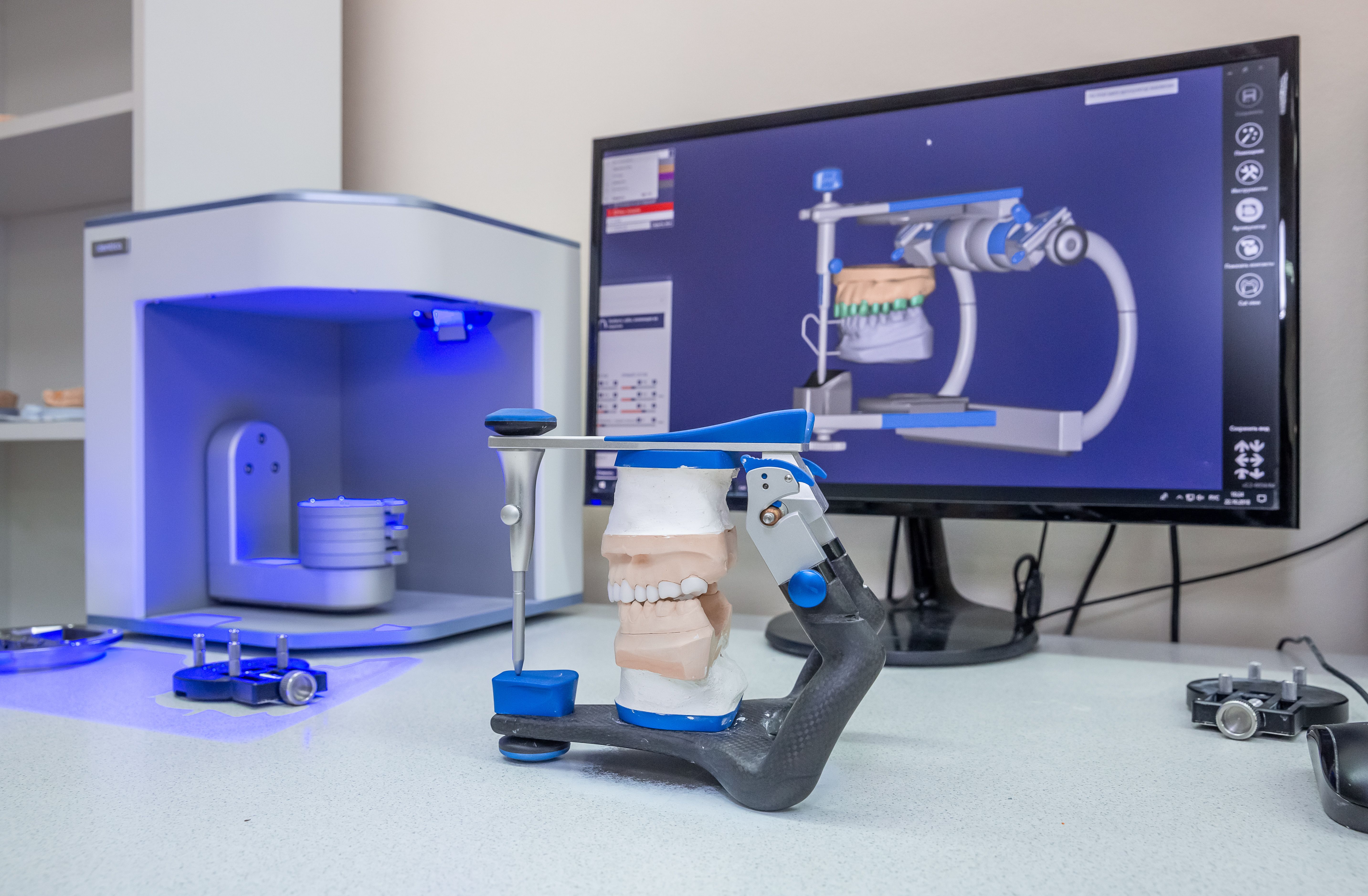 a dental scanner is sitting on a table next to a computer monitor .