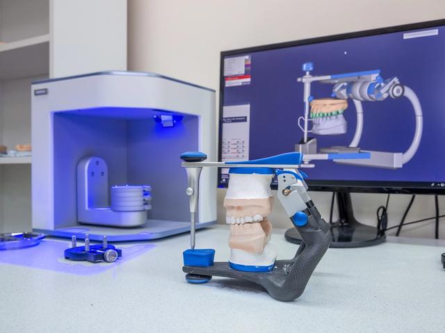 a dental scanner is sitting on a table next to a computer monitor .