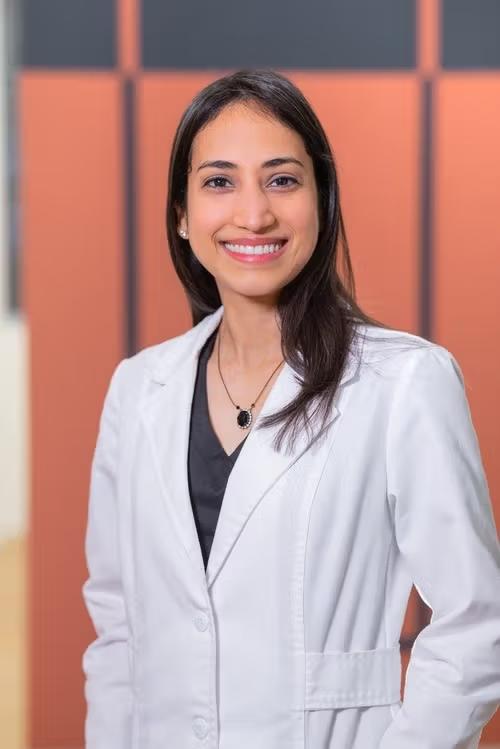 a woman in a white lab coat is smiling for the camera .