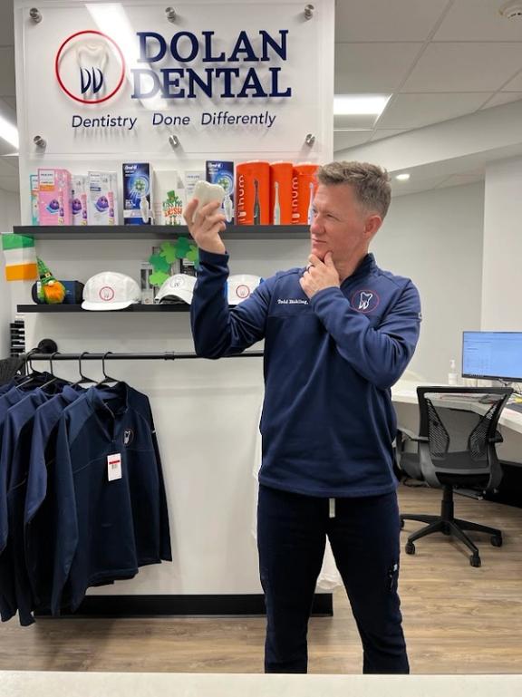 a man standing in front of a dolan dental sign