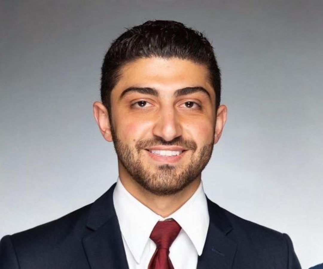 a man with a beard is wearing a suit and tie and smiling for the camera .
