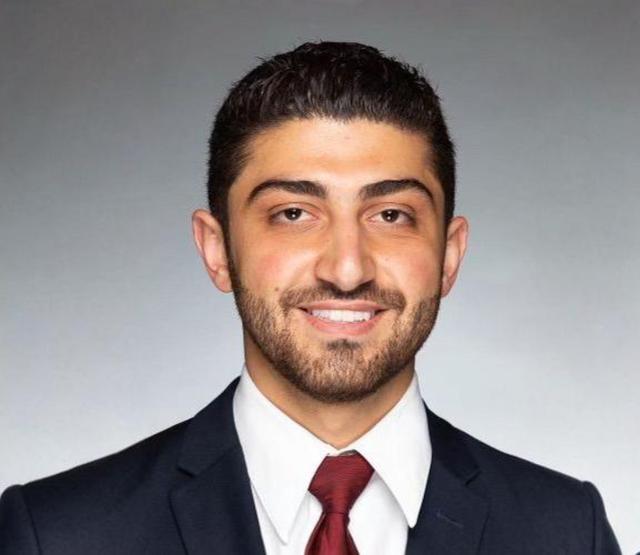 a man with a beard is wearing a suit and tie and smiling for the camera .