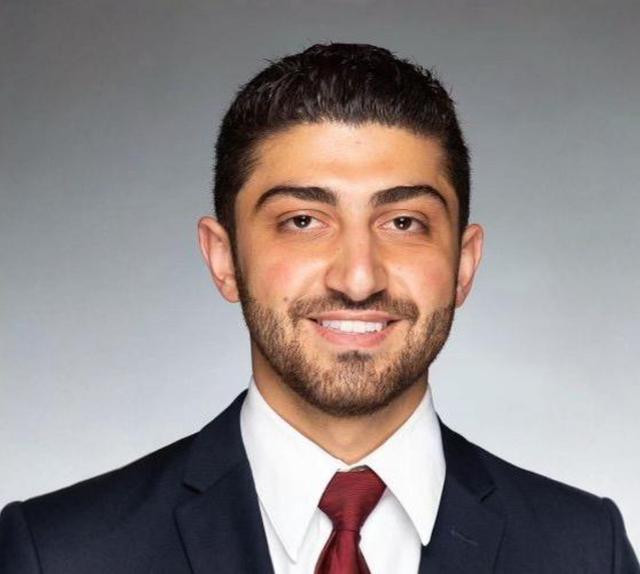 a man with a beard is wearing a suit and tie and smiling for the camera .