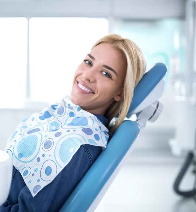 a woman is smiling while sitting in a dental chair .