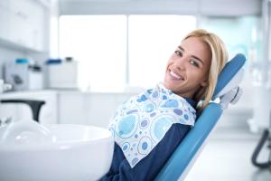 Smiling woman in a dental chair with a bib.