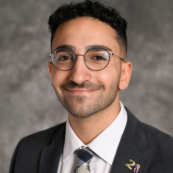 a man wearing glasses and a suit and tie is smiling for the camera .