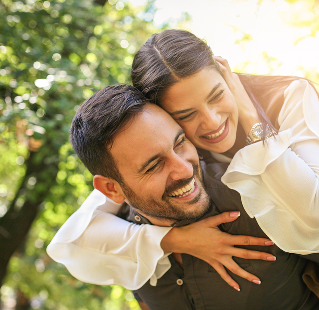 a man is carrying a woman on his back and both are smiling