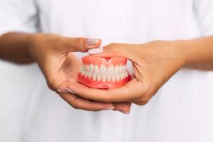 a woman is holding a denture in her hands .