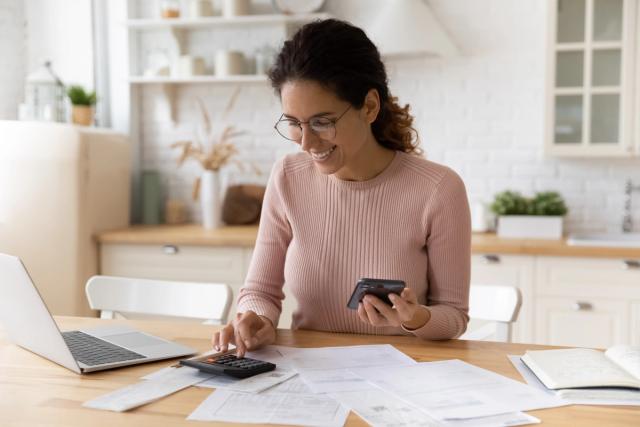 a woman is sitting at a table using a calculator and a credit card .