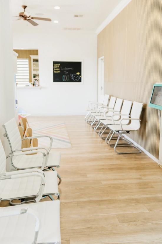 A modern, light-filled waiting room with rows of white chairs, wood floors, and a "Welcome to CDCC" chalkboard.
