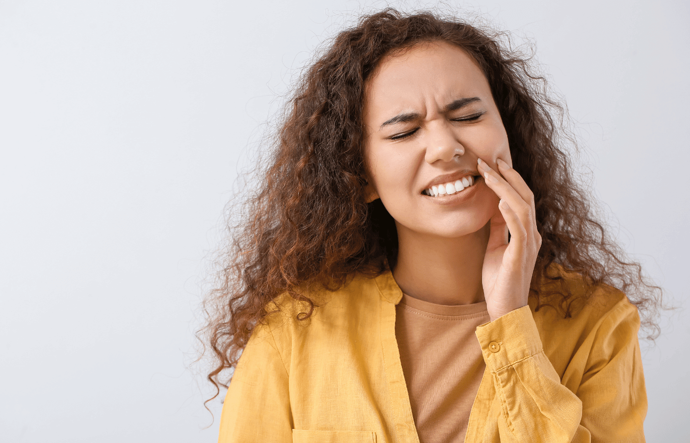 a woman in a yellow shirt has a toothache