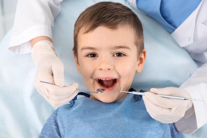 a young boy is having his teeth examined by a dentist .
