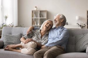 An older couple laughing heartily on a sofa.
