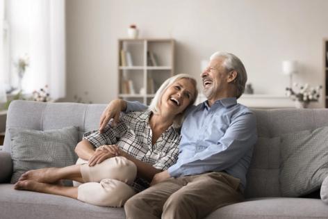 an elderly couple is sitting on a couch and laughing .