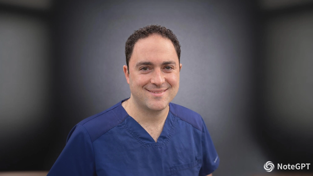 A smiling man with dark curly hair wears blue scrubs against a dark, blurred background.