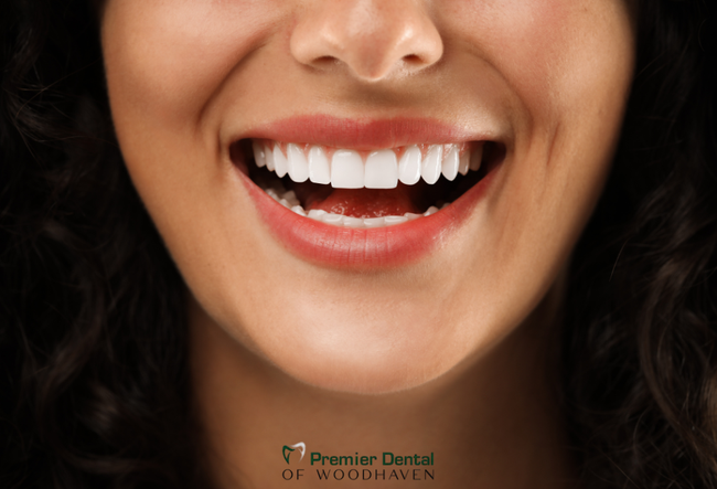 a close up of a woman 's mouth with the words premier dental of woodhaven on the bottom