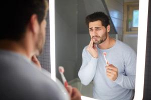 a man is brushing his teeth in front of a bathroom mirror.