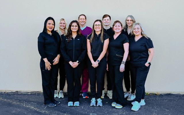 a group of people in scrubs are posing for a picture .