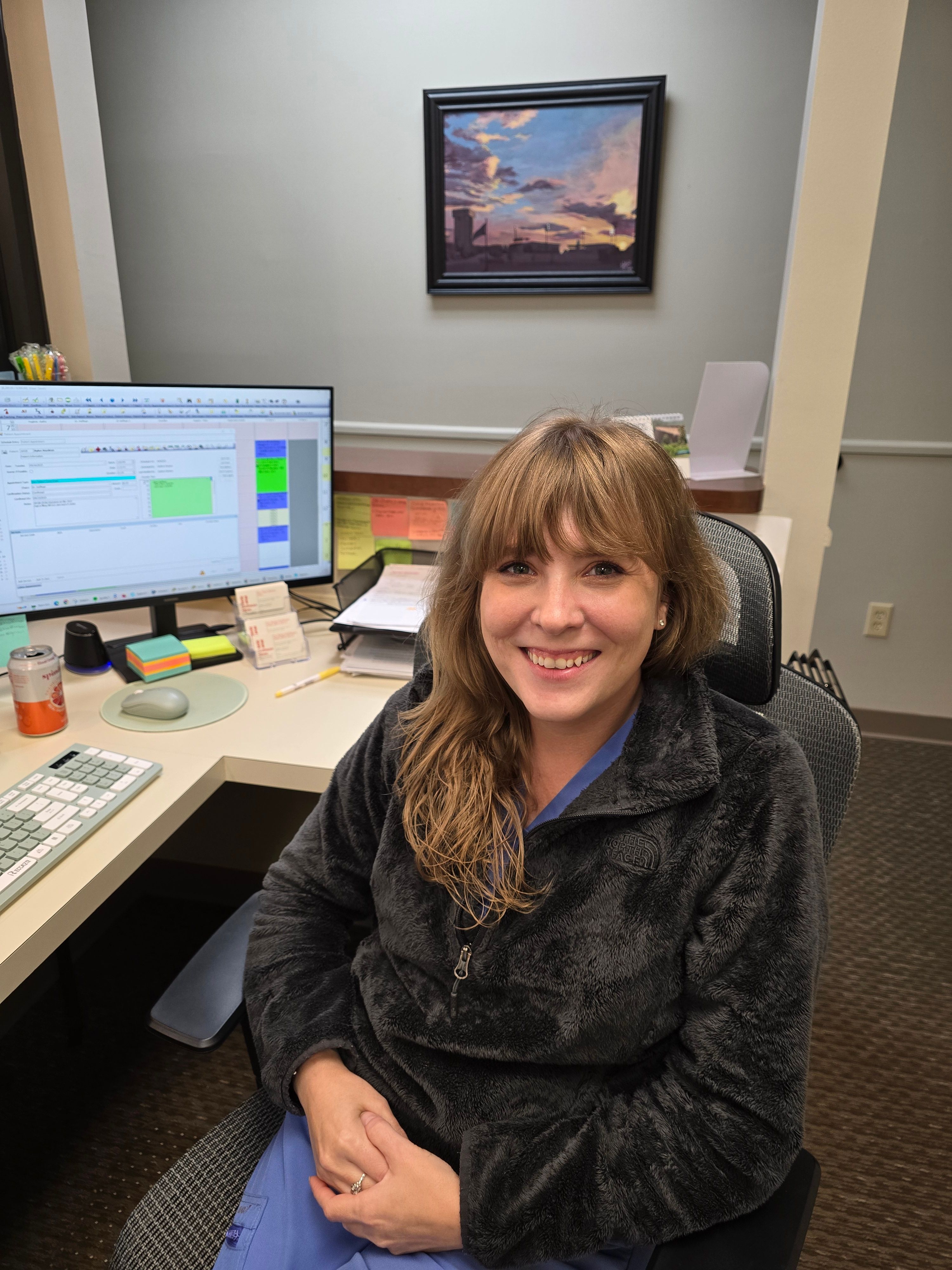 a woman is sitting in front of a computer and smiling