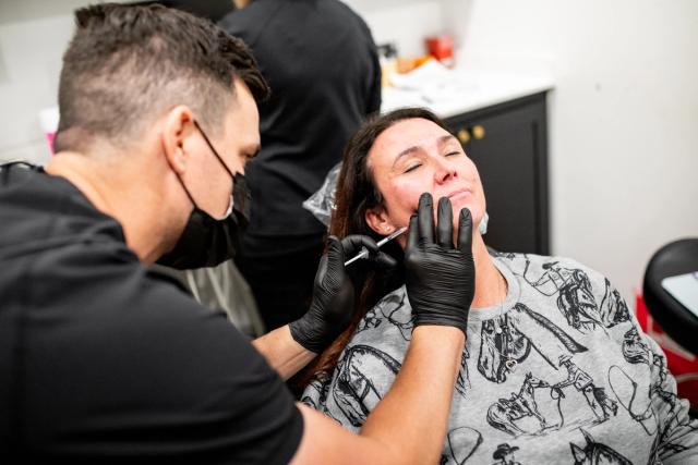 a man is giving a woman a botox injection in her face .