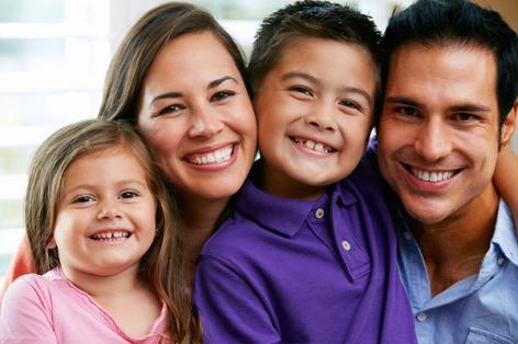 A happy family of four smiling at the camera.