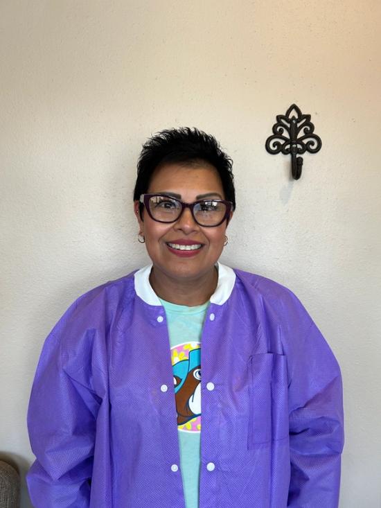a woman wearing glasses and a purple coat is smiling for the camera .