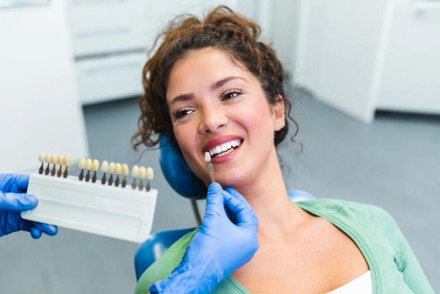 a woman is sitting in a dental chair while a dentist examines her teeth .