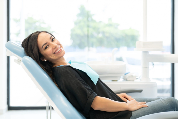 a woman is smiling while sitting in a dental chair