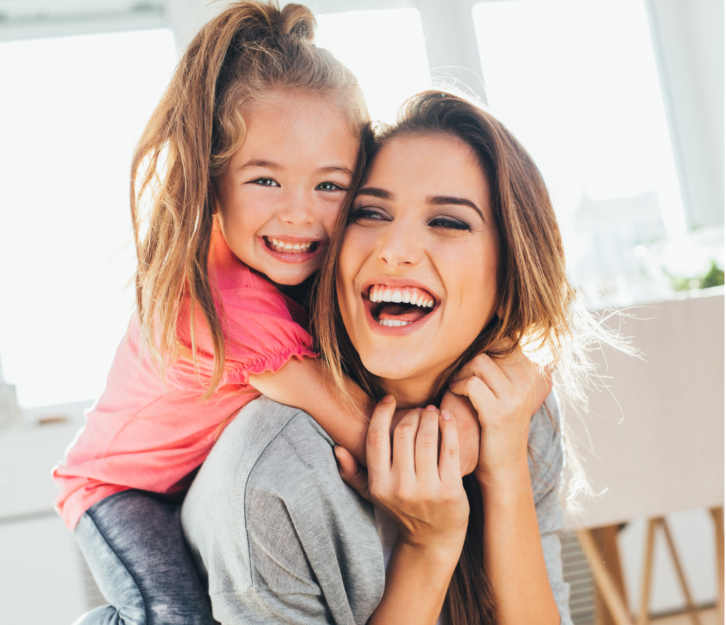 a woman is carrying a little girl on her back and both are smiling