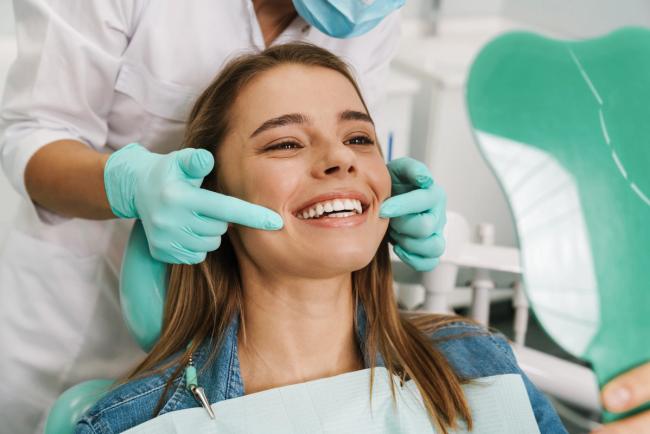 a woman is sitting in a dental chair while a dentist examines her teeth .