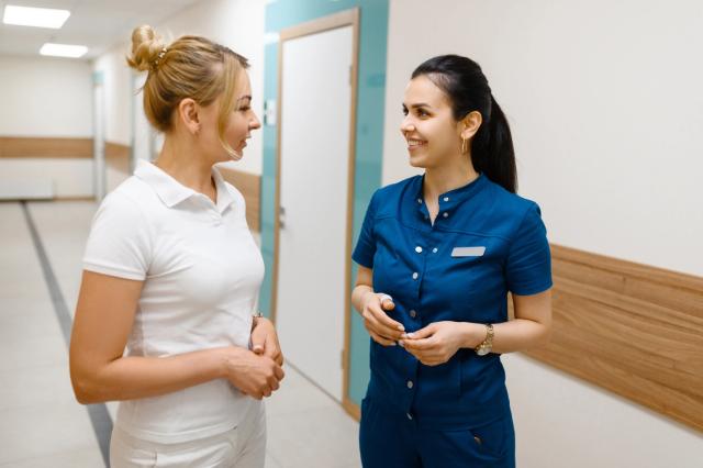 two female doctors are talking to each other in a hospital hallway .