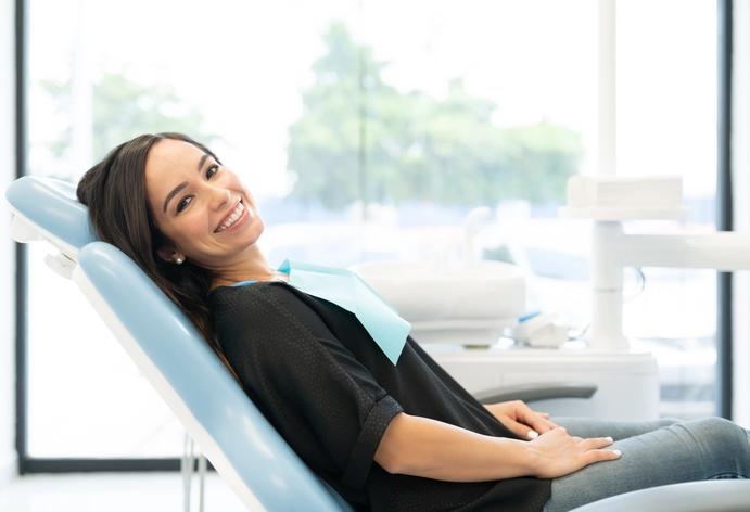 a woman is sitting in a dental chair and smiling .