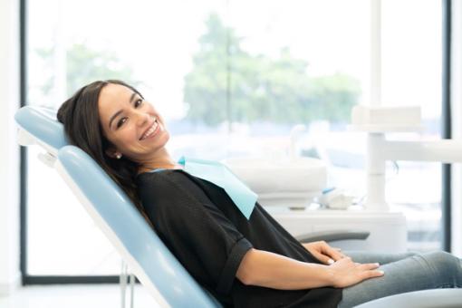 a woman is sitting in a dental chair and smiling .